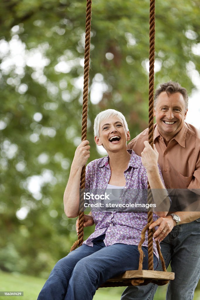 Uomo anziano, spingendo la moglie su un Altalena - Foto stock royalty-free di Altalena