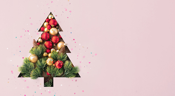 Creative Christmas tree with golden and red balls isolated on pink background. Banner for New Year's greetings.