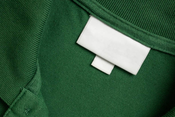 istock Blank white laundry care clothes label on green shirt fabric texture background 1563462915