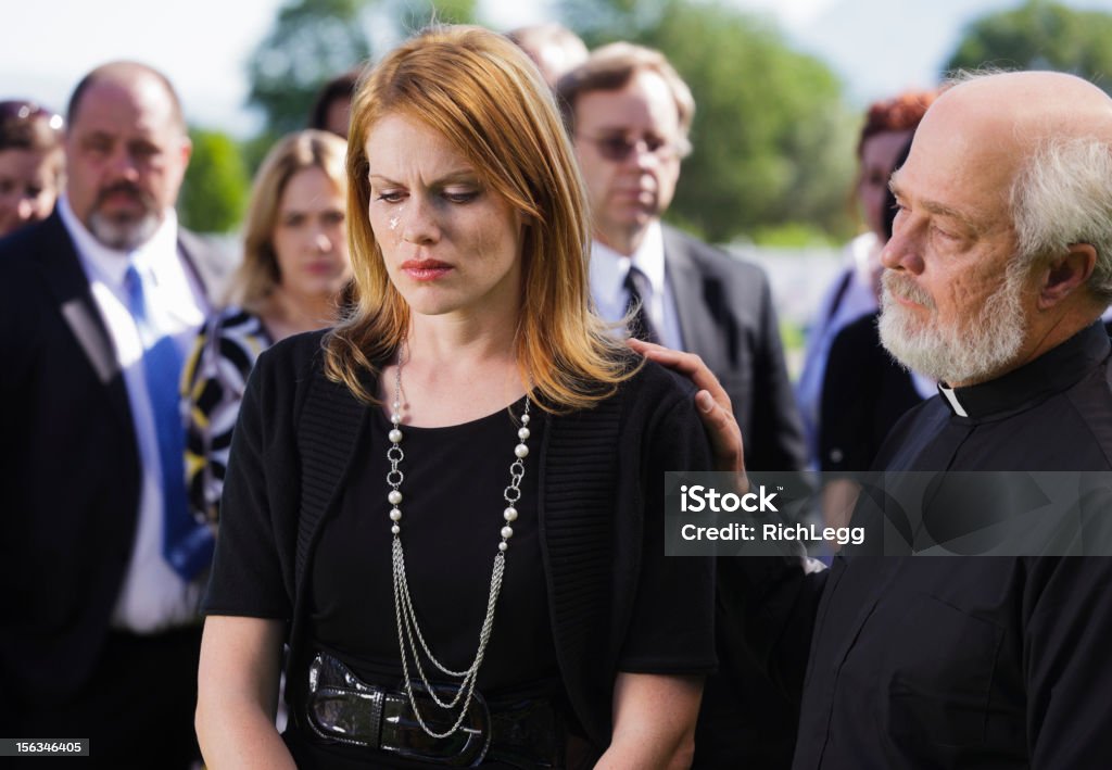 Widow at a Funeral A grieving widow standing graveside at a funeral. Funeral Stock Photo