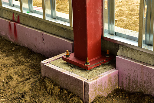 Concrete footing and steel support beam are part of construction for new commercial building.