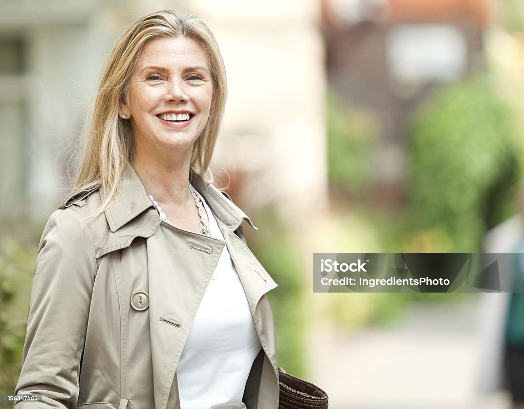 Una sonriente mujer madura en la calle con una bolsa. - Foto de stock de Adulto libre de derechos