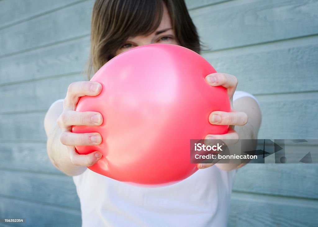 Squeezing Red Balloon Girl squeezing a red balloon, about to pop Balloon Stock Photo