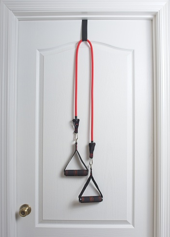 Home exercise bands hanging from a white door. Red surgical tubing stretchy exercise bands provide a convenient home workout.