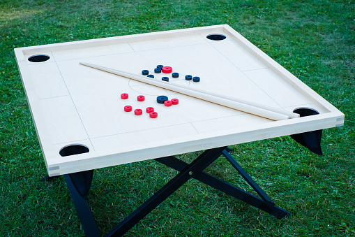 Novuss (also known as koroona or korona) is a large wooden board game where small wooden discs are hit with cue sticks into pockets.