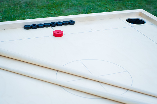 Novuss (also known as koroona or korona) is a large wooden board game where small wooden discs are hit with cue sticks into pockets.