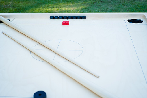 Novuss (also known as koroona or korona) is a large wooden board game where small wooden discs are hit with cue sticks into pockets.