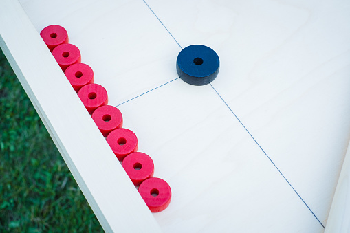 Novuss (also known as koroona or korona) is a large wooden board game where small wooden discs are hit with cue sticks into pockets.