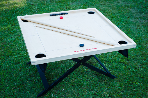 Novuss (also known as koroona or korona) is a large wooden board game where small wooden discs are hit with cue sticks into pockets.