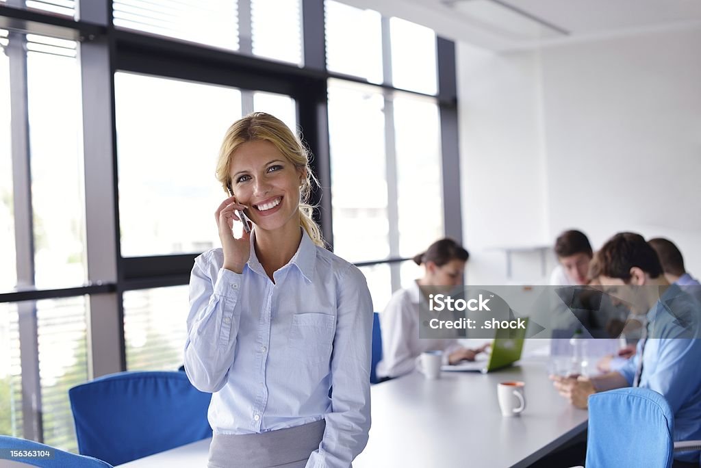 Donna d'affari con il suo staff in fondo all'ufficio - Foto stock royalty-free di Adulto