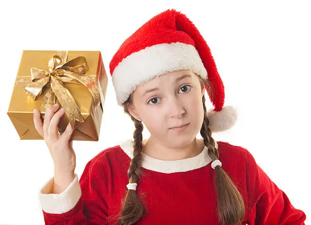 Beautiful girl dressed in Christmas clothes and red santa hat with present in her hand isolated on white background