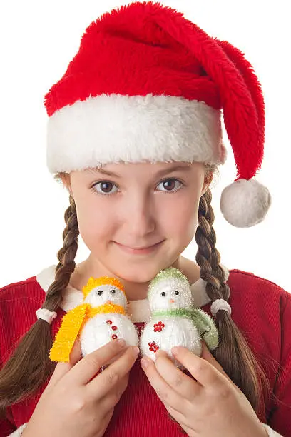 Beautiful girl dressed in Christmas clothes and red santa hat with two cute little snowmen in her hands isolated on white background