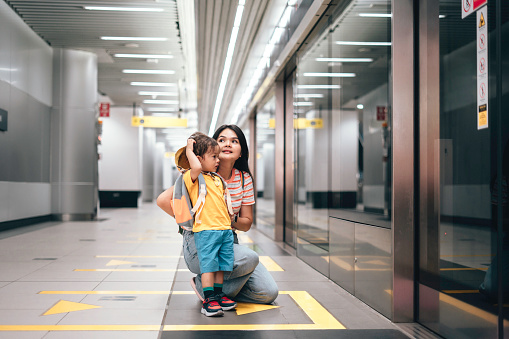 Mother And son carrying rucksack Standing Together At Subway Station