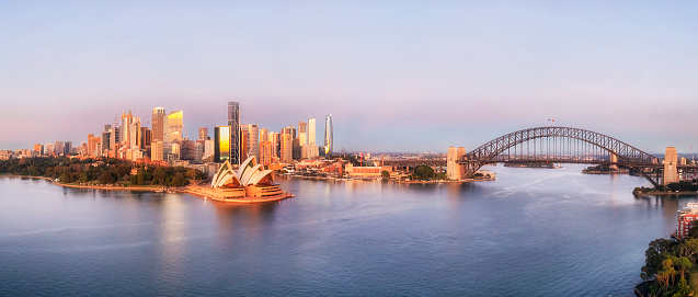 Close sunrise lit cityscape of City of Sydney harbour waterfront architecture landmarks in aerial panorama.