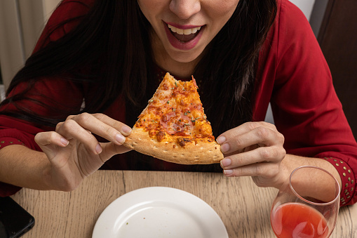 taking a bite of a piece of pizza, appetizing fast food as wallpaper in studio, unhealthy eating, food