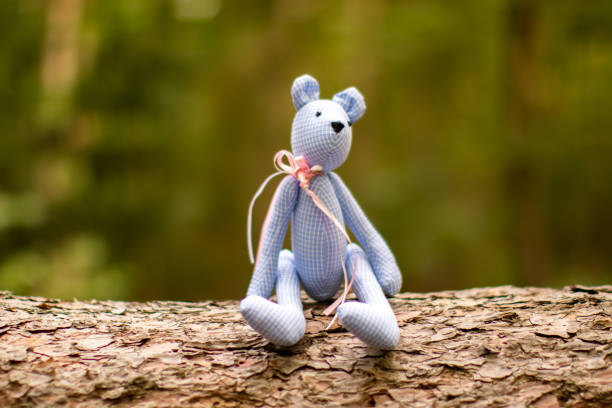 toy bear sits on a tree trunk in the forest