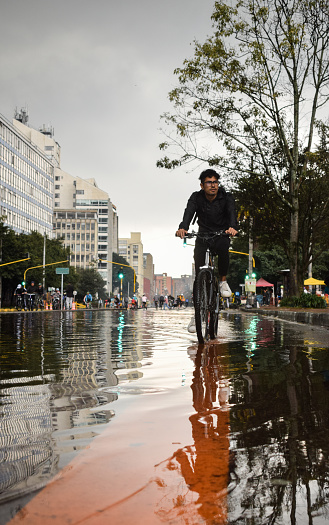 Young man riding a bicycle in a flooded street in Bogota, Colombia.