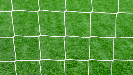 Close up of a soccer net on green grass background on football field. Sport bets in betting shops.