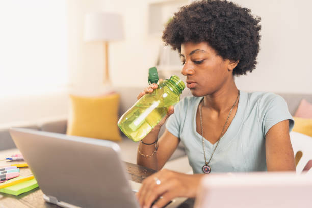 istock Young black woman drinking water and working on laptop 1563768295