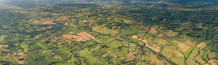 Vibrant green crops, ploughed fields and pasture, hedgerows and woodland surrounding farms and villages in an idyllic rural patchwork quilt landscape from high above. ProPhoto RGB profile for maximum color fidelity and gamut.