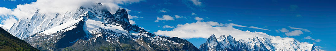 The snow capped summit and dramatic hanging glaciers of the Aiguille Verte (4122m) overlooking the iconic pillar of Les Drus, the Col des Montets and the swirling clouds below under panoramic deep blue skies, Mont Blanc Massif, France. ProPhoto RGB profile for maximum color fidelity and gamut.