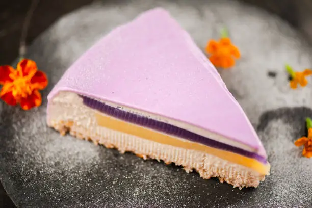 A slice of Gourmet Ube Entremet Cake also known as purple yam with layered sponge cake, ube jelly, evaporated milk jelly, and ube mousse, covered in a mirror glaze.
