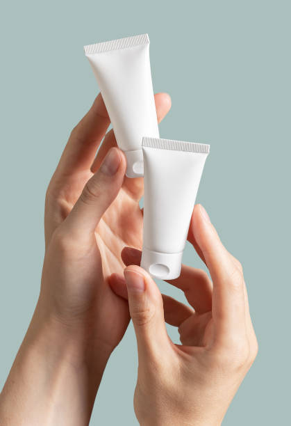 istock Hand holding two small cream tubes mock-ups 1563829342