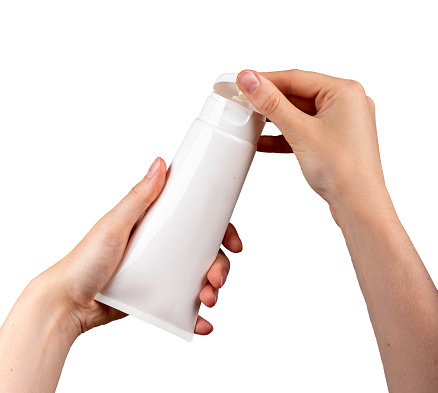 Hands holding cream tube mock-up, blank beauty product, moisturizer mockup isolate on white, opening lid, cap.