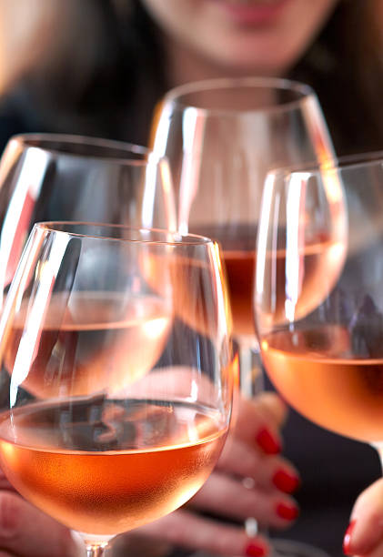 Toasting With Wine Closeup of four glasses with wine being clinked together during a toast at a celebration rosé wine stock pictures, royalty-free photos & images