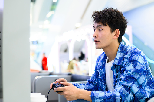 Asian young man playing video game with game controller