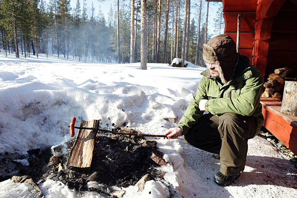 istock Man Cooking Sausages over a Fire Outdoors 156409069
