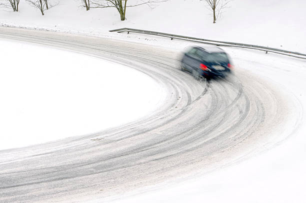 istock snowfall on the road, slippery way with car 156410689
