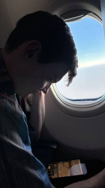 istock Portrait Young Man Traveling By Air Looking Down at Mobile Device 1564110023