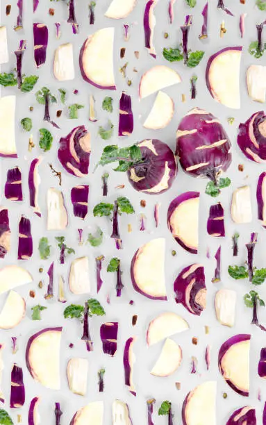 Abstract background made of Kohlrabi vegetable pieces, slices and leaves isolated on gray background.