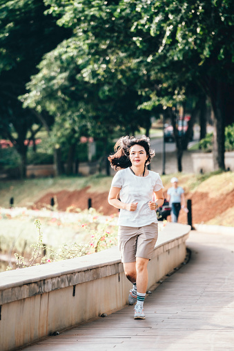 young athletic woman running on the road in the city park