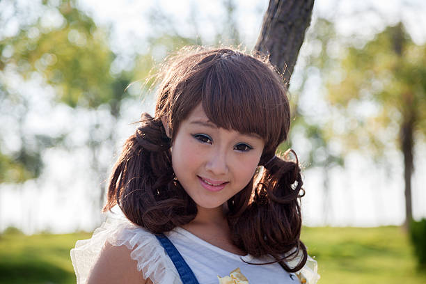 asian female in summer standing next to a tree