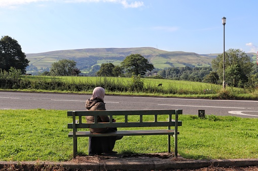 A person sits on a park bench surrounded by natural beauty.