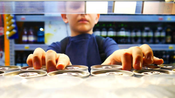 Close-up of many cans of soda on a store shelf and a boy takes two stock photo