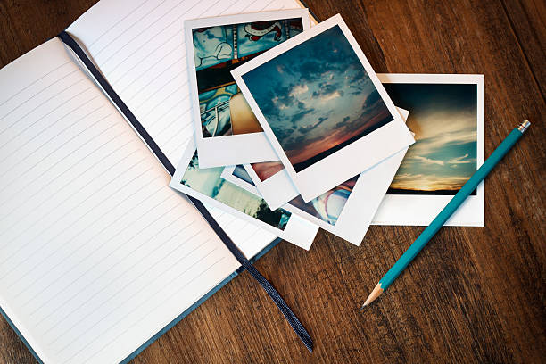 Writing about Memories Vintage polaroid pictures from the 1970's with an  open journal and pencil. Polaroids are from the photographer's childhood and owned by the photographer. table photos stock pictures, royalty-free photos & images