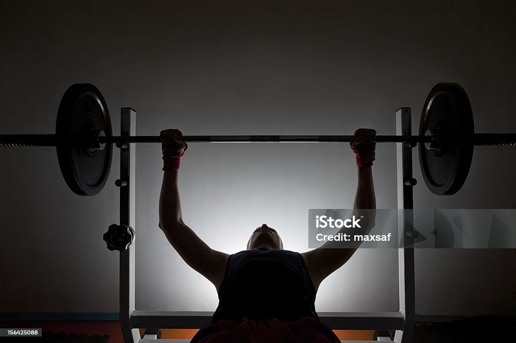 Man weightlifter at the gym Man weightlifter at the gym, lifting weights on a benchpress Bench Press Stock Photo