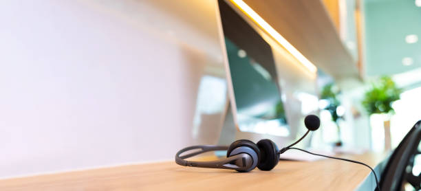 istock headset on desk with computer desktop at customer service and marketing support workplace. Office supplies of customer service. Communication support, call center and helpline concept. 1564266441