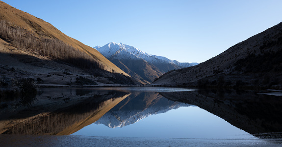 Mountain landscape with a lake that has good reflections. Features snow and sunrise near Queenstown New Zealand.
