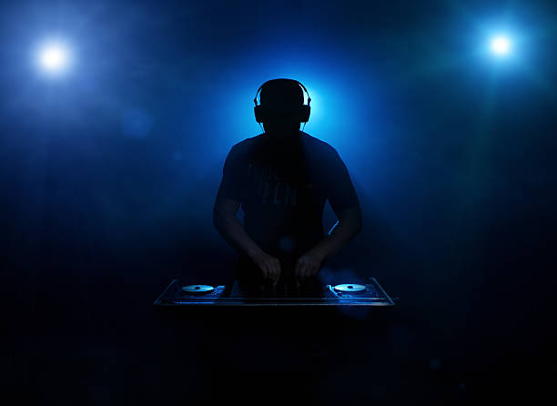 DJ silhouette Silhouette of a disc jockey mixing in the night club with copy space synthpop stock pictures, royalty-free photos & images