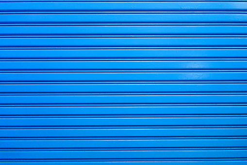 Security roller shutter door by stanless steel blue color of industrial factory building for entrance to storage in warehouse with stripes style textured background