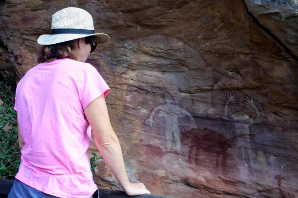 donna australiana guarda la pittura di arte rupestre indigena australiana penisola di cape york queensland australia - aboriginal rock art foto e immagini stock