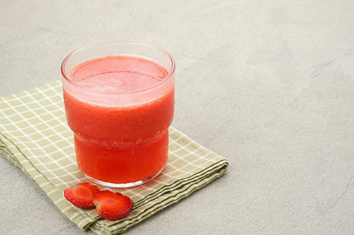 Glass of strawberry juice with strawberry fruit on wooden table