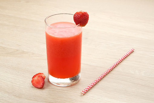 Glass of strawberry juice with strawberry fruit on wooden table