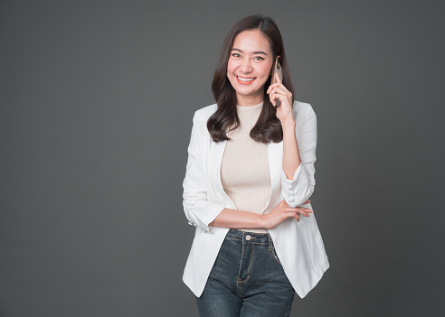 Smiling asian businesswoman standing with arms folded and looking at camera isolated over gray background. Successful