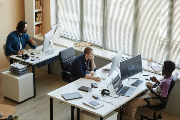 istock Young intercultural coworkers having snacks in front of computer screens 1564342574