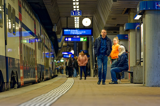 Train passengers at platform of railway station Stettbach on a cloudy spring day. Photo taken May 17th, 2023, Stettbach, Switzerland.